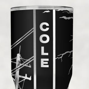 Op de afbeelding: Een zwarte cilindrische beker met een verticale witte streep met de naam COLE in dikke witte hoofdletters. Het ontwerp bevat een witte afbeelding van een elektriciteitsmast met lijnen aan de linkerkant en een silhouet van een tak aan de rechterkant.