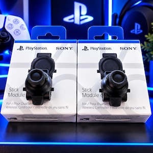 May include: Two white and blue retail boxes for PlayStation Sony Stick Module replacement parts for DualSense wireless controllers. Each box features a black circular joystick component with a textured grip surface and a circular base plate.