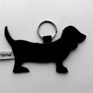May include: Black leather dachshund keychain with a silver key ring and a white tag that says "sew".