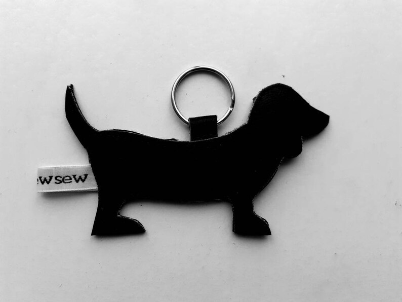 May include: Black leather dachshund keychain with a silver key ring and a white tag that says "sew".