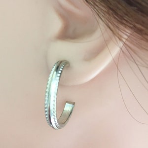 May include: Silver hoop earrings with a textured design.