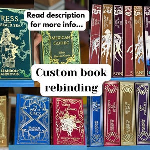 Può includere: Una collezione di libri di rilegatura personalizzati con scritte e disegni in lamina d'oro. I titoli includono "Tress of the Emerald Sea" e "The Way of Kings". I libri sono esposti su scaffali blu, con il testo "Custom book rebinding".