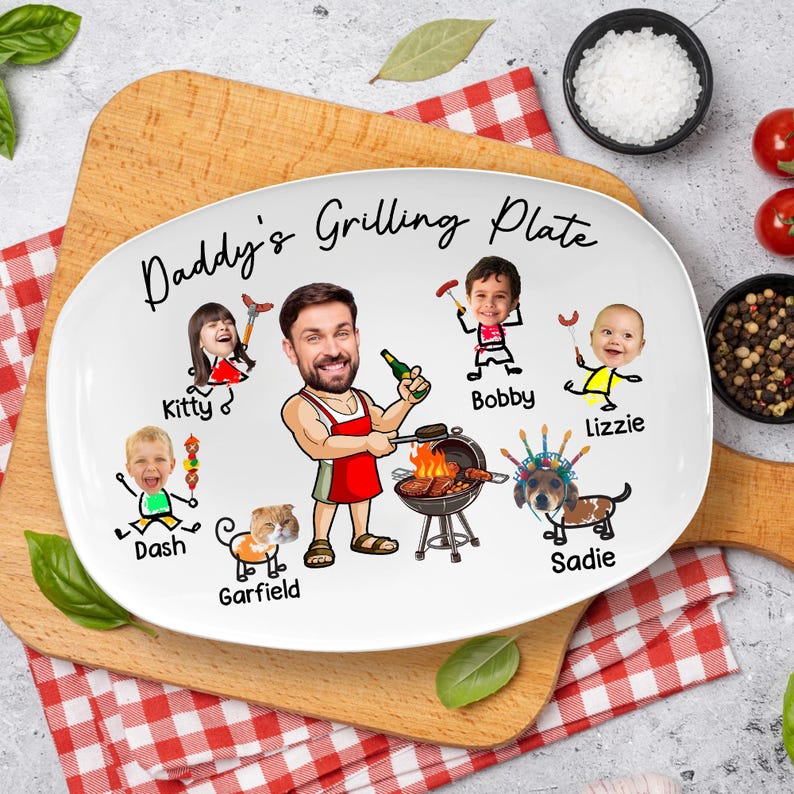May include: A white oval ceramic plate featuring the text Daddy's Grilling Plate and a cartoon illustration of a person in a red apron grilling, surrounded by smaller cartoon figures labeled Kitty, Bobby, Lizzie, Dash, Garfield, and Sadie.