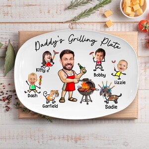 May include: A white oval ceramic serving plate featuring the text Daddy's Grilling Plate. The design includes a central cartoon figure in a red apron grilling, surrounded by illustrated stick figures with photographic faces labeled Kitty, Dash, Garfield, Bobby, Lizzie, and Sadie.