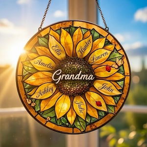 May include: A round, stained-glass sunflower with the word "Grandma" in the center. The yellow petals have names like "Ella" and "Ashley" written on them. The sunflower is framed in a dark brown border and hangs from a chain.