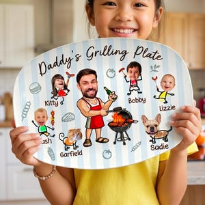 Può includere: Un piatto ovale personalizzato con sfondo a righe blu e bianche. Il piatto presenta illustrazioni di cartoni animati di una famiglia e il testo "Daddy's Grilling Plate".