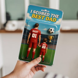 May include: A Father's Day gift set with two red soccer-uniformed figurines, labelled "Daddy 01" and "Owen 22," holding hands. Includes a football and a gold trophy, presented in a blister pack with the text "I SCORED THE BEST DAD - HAPPY FATHER'S DAY."
