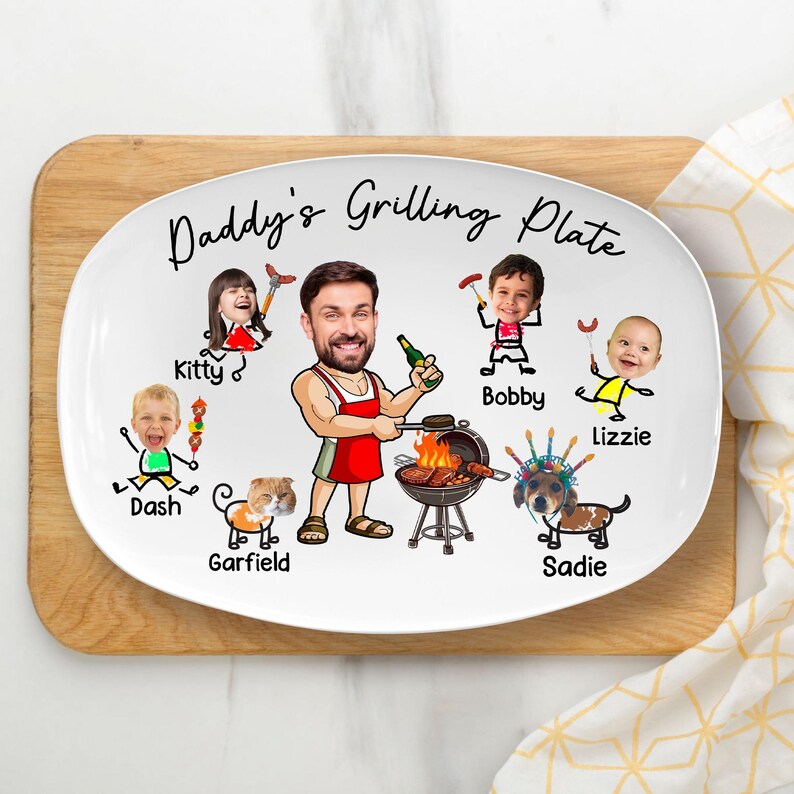 May include: A white oval ceramic plate featuring the text Daddy's Grilling Plate. The design includes a central illustration of a man in a red apron grilling, surrounded by cartoon-style drawings of children and pets with photographic faces.