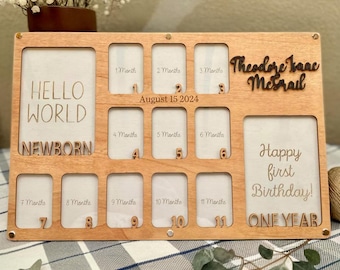 Puede incluir: Marco de fotos de hitos de bebé de madera con espacios para 12 fotos, etiquetado como "Hello World Newborn" y "Happy first Birthday! ONE YEAR". Incluye el nombre "Theodore Isaac Mcgrail" y la fecha "15 de agosto de 2024".