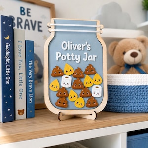 May include: A light blue wooden jar-shaped sign with the text Oliver's Potty Jar. The sign features attached wooden icons of smiling brown poop emojis, yellow water droplets, and white toilet paper rolls, all held by a white elastic band.