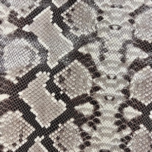 May include: Close-up of a snakeskin pattern with a black and white color scheme. The pattern is made up of small, overlapping scales.