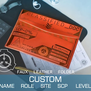 Peut inclure: Un dossier en similicuir orange avec le texte "CLASSIFIED_DOC" et "SCP-096". Le dossier a un design personnalisé avec les mots "NAME", "ROLE", "SITE", "SCP" et "LEVEL". Le dossier contient également le texte "VISUAL EVIDENCE PHOTOGRAPHIC".