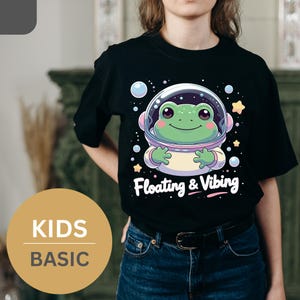 Camiseta infantil flotante y vibrante con adorable rana astronauta. Regalo ideal para niños y familia (BÁSICA).
