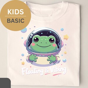 Camiseta infantil flotante y vibrante con adorable rana astronauta. Regalo ideal para niños y familia (BÁSICA).