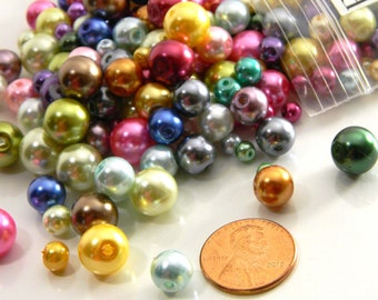May include: A close-up of a variety of colorful pearl beads in a plastic bag. The beads are a mix of colors, including pink, green, blue, purple, and gold. The beads are all about the same size and are perfect for crafting.