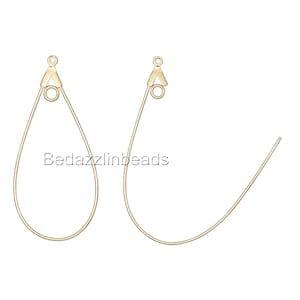 May include: Two gold-toned earring hoops with a teardrop shape and a small jump ring at the top. The hoops are made of thin wire and are designed to be used for hanging charms or other jewelry.