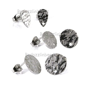 May include: A collection of silver-toned stud earrings with textured surfaces. The earrings come in teardrop, oval, and circular shapes. Each earring has a post for insertion and a small hole for attaching additional elements.