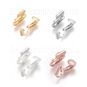 Könnte beinhalten: Vier Paar Ohrclips in Gold, Silber und Roségold. Jedes Paar hat ein kleines, rundes, strukturiertes Stück auf der einen Seite und ein längeres, zylindrisches Stück auf der anderen Seite.