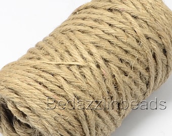 May include: A close-up of a roll of natural brown twine. The twine is made of jute and is perfect for crafting, wrapping, and decorating.