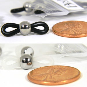May include: Two close-up images of black and white eyeglass retainers with a silver metal bead. The retainers are shown next to a US penny for size comparison.