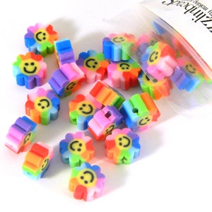 May include: A bag of colorful flower-shaped beads with a smiley face on each bead. The beads are made of plastic and have a rainbow color scheme.