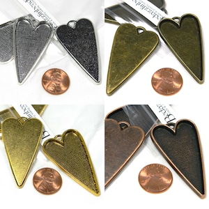 May include: Four heart-shaped metal pendant trays in different finishes: silver, black, brass, and copper. Each tray is approximately the size of a US penny.