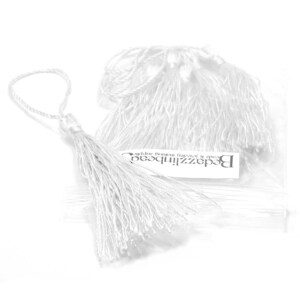 May include: A package of white silk tassels, with a label that reads "BeadzilliBead  beads & jewelry making supplies".