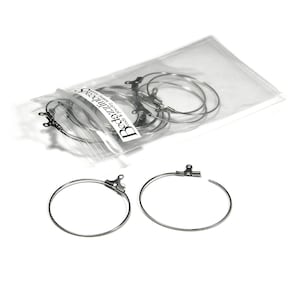 May include: A package of silver hoop earrings with a clasp closure. The package is labeled "Beadzilli" and says "curve & dangle earrings".