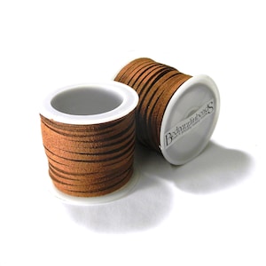 May include: Two spools of brown suede cord, each wrapped in white plastic with a label that reads "Bedazzlinbeads".