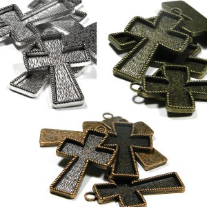 May include: A set of six metal cross charms with a textured surface. The charms are in silver, bronze, and antique gold finishes. They are perfect for jewelry making or crafting.