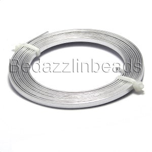 Puede incluir: Una bobina de alambre plano plateado, enrollado firmemente y asegurado con una brida de plástico blanco. El alambre es liso y reflectante, ideal para la fabricación de joyas o manualidades. El texto "Bedazzlinbeads" está impreso en el alambre.