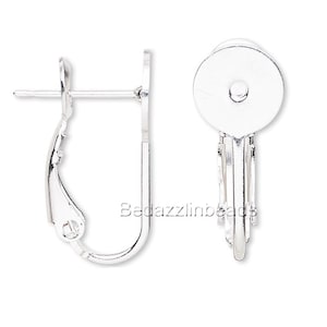 May include: A pair of silver-toned earring findings with a round, flat back and a curved, open-back design. The findings are designed to hold a bead or other embellishment.