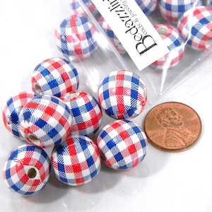 Może przedstawiać: Zbliżenie na drewniane koraliki w czerwono-biało-niebieską kratę. Koraliki są mniej więcej wielkości polskiego grosza.
