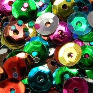 May include: Assortment of colorful iridescent sequins in various shapes and sizes. The sequins are made of plastic and have a shiny, reflective finish.