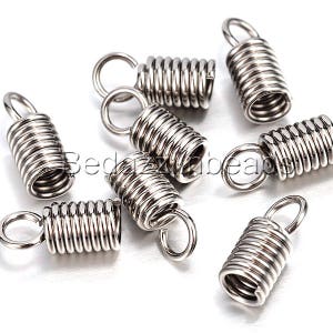 May include: A collection of silver-colored metal coil crimp end findings with attached loops. These jewelry-making components are designed to secure and finish the ends of cords or strands in jewelry designs.
