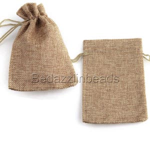 Puede incluir: Dos pequeñas bolsas de yute marrones con cordón. Las bolsas están hechas de un tejido natural tejido y tienen un aspecto rústico.