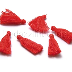May include: Six red fabric tassels with a loop at the top. The tassels are about 1 inch long.