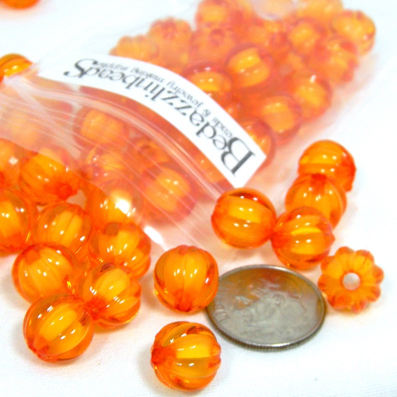 Puede incluir: Una bolsa de cuentas naranjas con forma de calabaza. Las cuentas son del tama&ntilde;o aproximado de una moneda de diez centavos. La bolsa est&aacute; etiquetada como "Beadz n' Speadz".