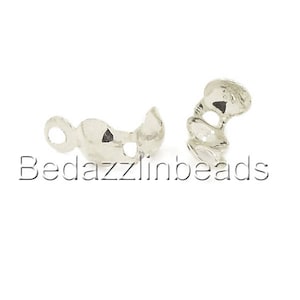 May include: Two silver-colored bead caps with a textured finish. One cap has a loop, and the other has a curved design. The text "Bedazzlinbeads" is printed in black below the bead caps. These caps are used for jewelry making.