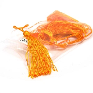 May include: A bag of bright orange tassels, perfect for adding a pop of color to crafts and projects.