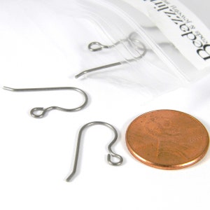 May include: Three silver earring hooks, each with a small loop at the top, are displayed on a white surface next to a US penny for size comparison. The penny is dated 2019.