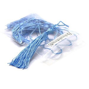 May include: A bag of light blue silk tassels, approximately 1 inch long, with a white label that reads "Speechless Beads" and "Handmade from 100% Silk".