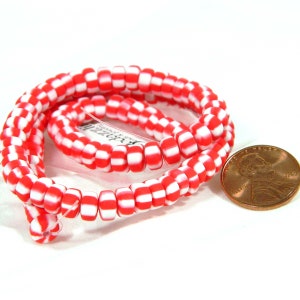 May include: A strand of red and white checkerboard glass beads. The beads are approximately the size of a US penny.