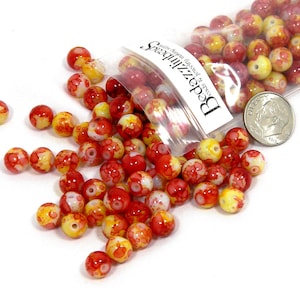 May include: A bag of red and yellow glass beads with white speckles. The bag is labeled "Beadzizzles" with the text "Love & Sparkle" and "Glass Beads from around the world".