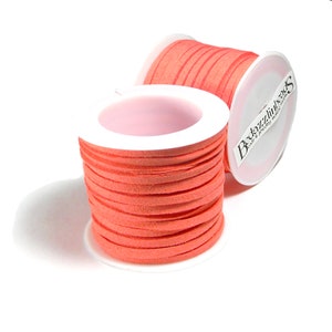 May include: Two spools of coral orange suede cord, each wrapped in white paper with a pink center. The label on one spool reads "Bedazzlinbeads".