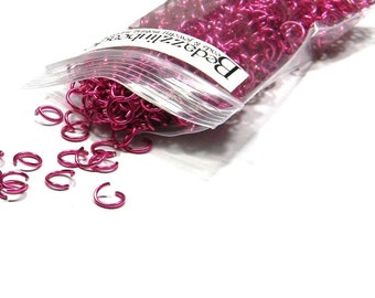 May include: A clear plastic bag filled with bright pink metal jump rings. The bag is labeled "Beadzilla" and "Made in Taiwan".