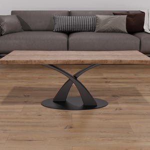 May include: A modern coffee table with a rectangular, light brown tabletop and a black, crossed-leg base. The table is in front of a gray sofa with decorative pillows and a blanket. The floor is made of wood.
