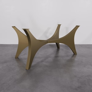 May include: A gold metal table base with a unique, modern design. The base has a curved, geometric shape with four legs that extend outwards.