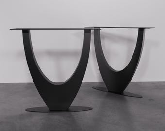 May include: Two black metal table legs with a unique U-shaped design. The legs are made of sturdy metal and have a sleek, modern look.