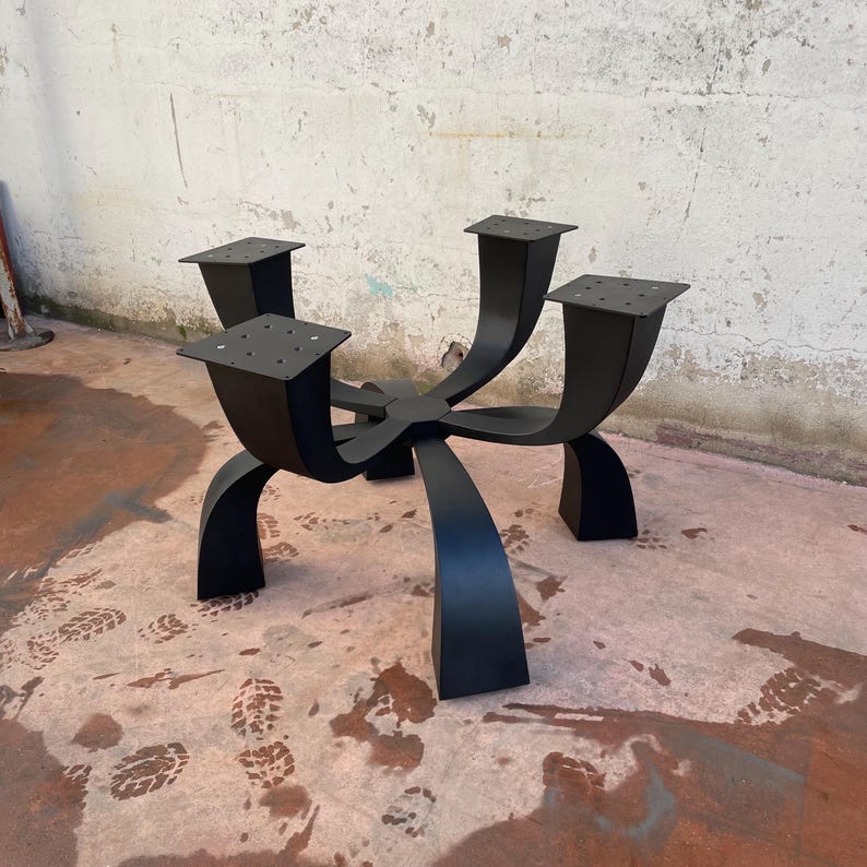 May include: Black metal table base with five legs that curve upwards and connect at the top. The base has a starburst design.